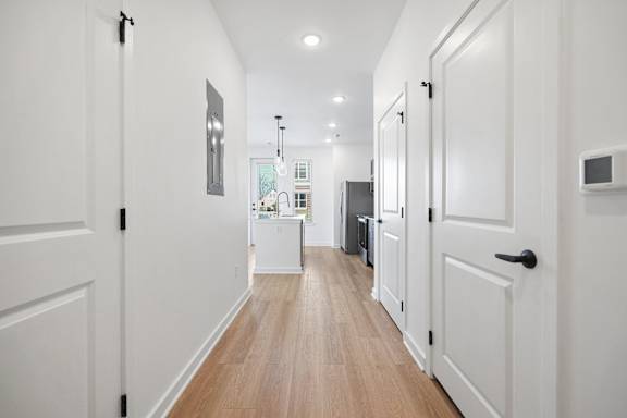 A long hallway with white doors and a white wall.
