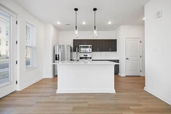 A modern kitchen with a white island and wooden floors.