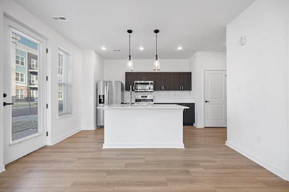 A modern kitchen with a white island and wooden floors.