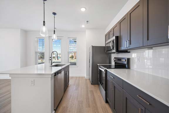 A modern kitchen with dark brown cabinets and stainless steel appliances.