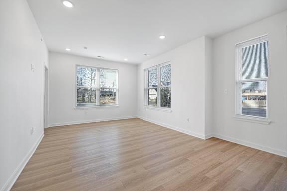 A spacious room with wooden flooring and windows.