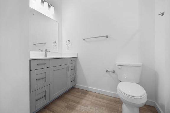 A white toilet sits in a bathroom with a white cabinet and a white sink.