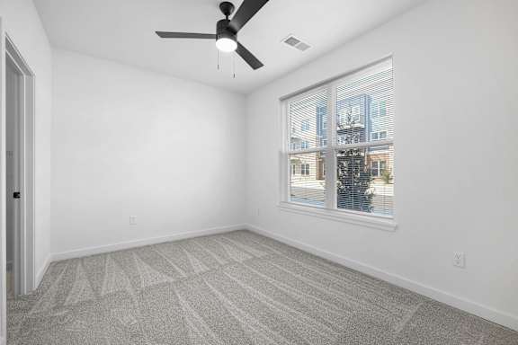 A room with a ceiling fan and a large window.