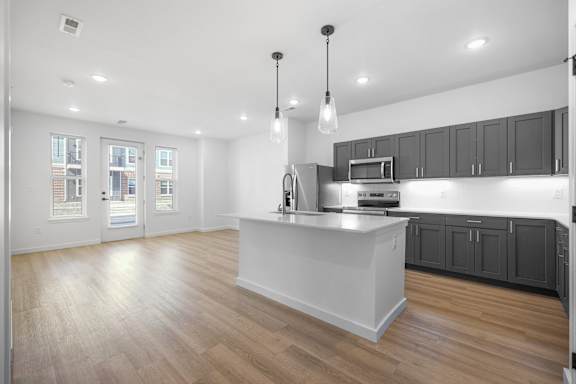A kitchen with a white island and wooden floors.