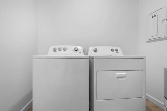 Two white washing machines in a laundry room.
