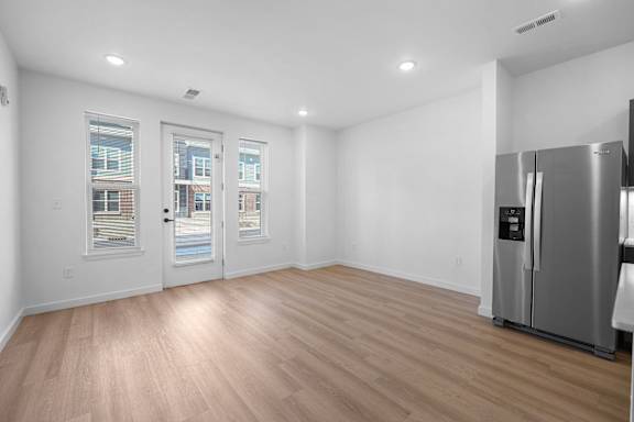 A kitchen with a refrigerator and wooden flooring.