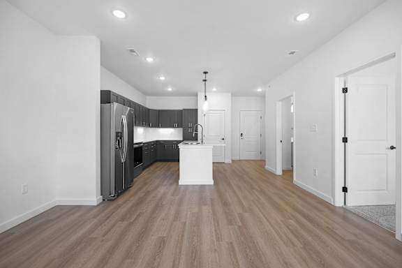 A kitchen with a refrigerator, sink, and cabinets.