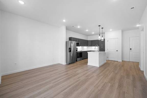 A kitchen with a refrigerator, sink, and cabinets.