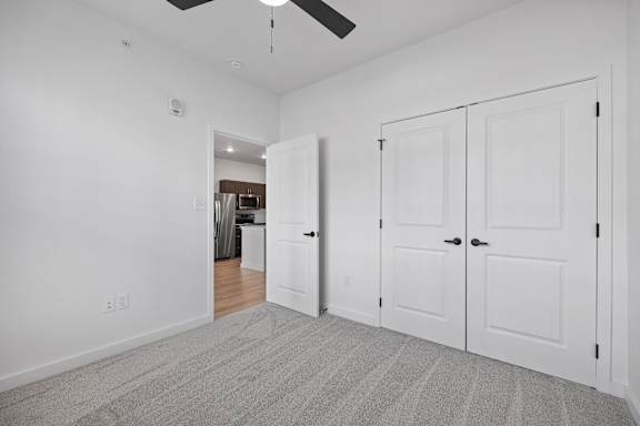 A room with a ceiling fan and three white doors.