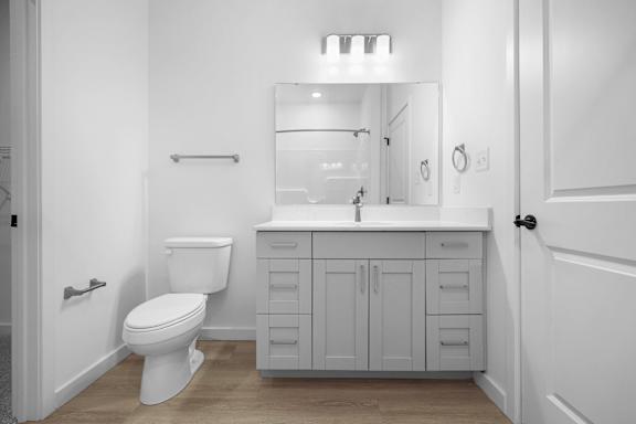 A white bathroom with a toilet, sink, and mirror.