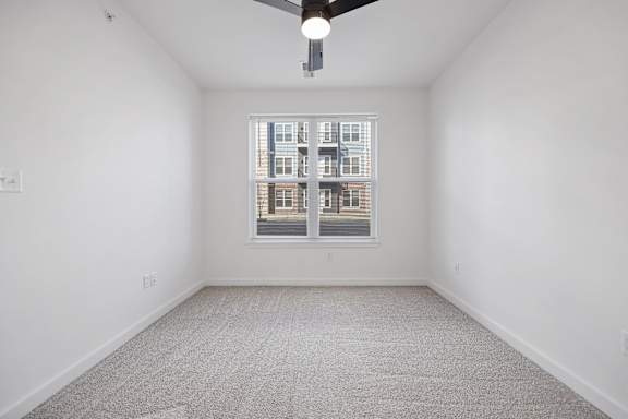 A room with a carpeted floor and a window showing a building outside.
