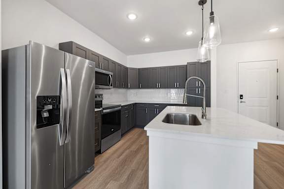 A modern kitchen with a stainless steel refrigerator and wooden floors.