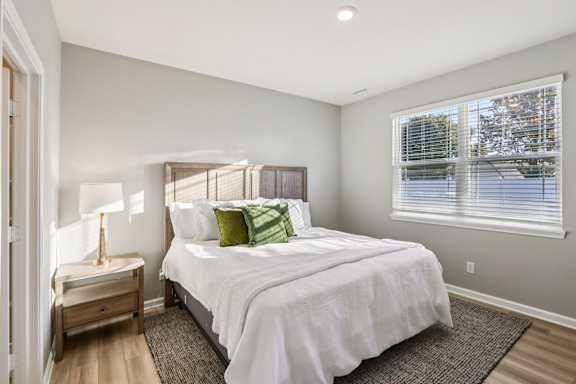 A bedroom with a large bed and a window with blinds.