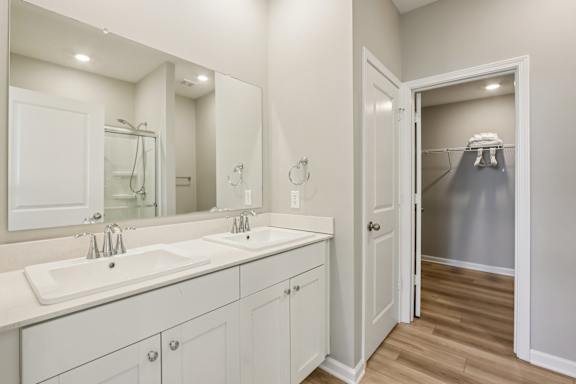 A bathroom with a double sink vanity and a walk-in shower.