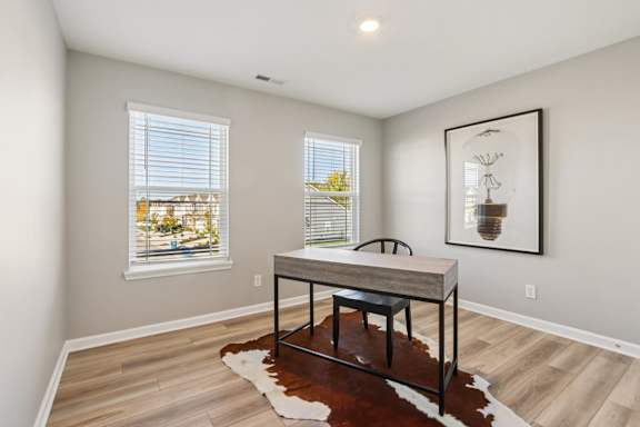 A room with a table and a cowhide rug in front of a window.
