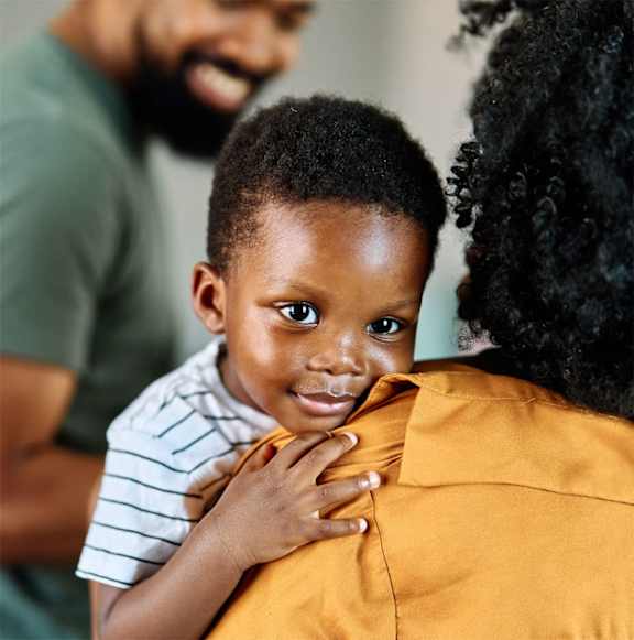 A young child is being held by an adult in a yellow shirt.