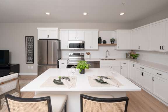 A modern kitchen with a dining table set for two.