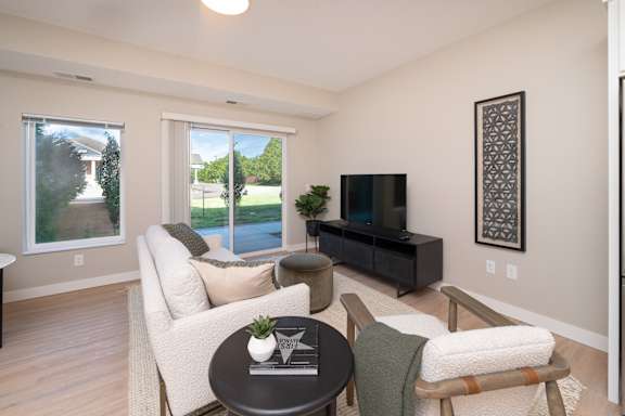 A living room with a white couch, a black coffee table, and a flat screen TV.