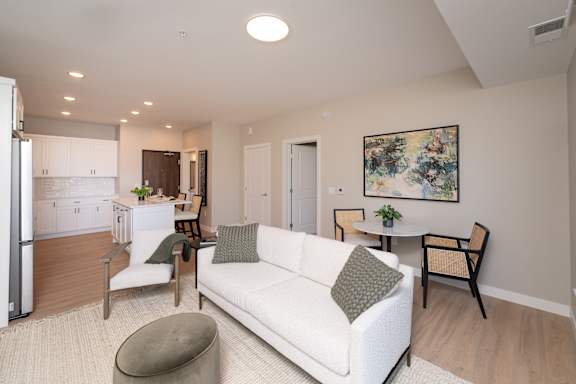 A modern living room with a white couch and a painting on the wall.