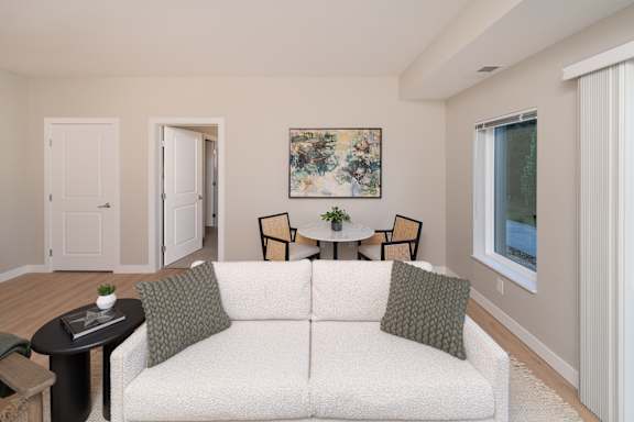 A living room with a white couch and a painting on the wall.