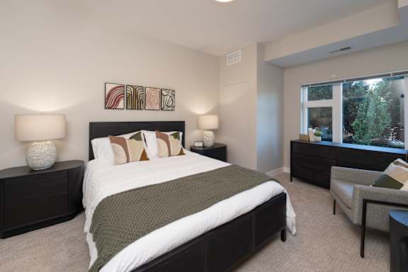 A bedroom with a large bed and a chair.