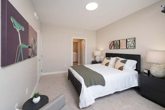 A bedroom with a large bed and a painting of a bicycle on the wall.