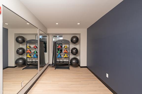 A gym with a mirror, weights, and exercise balls.