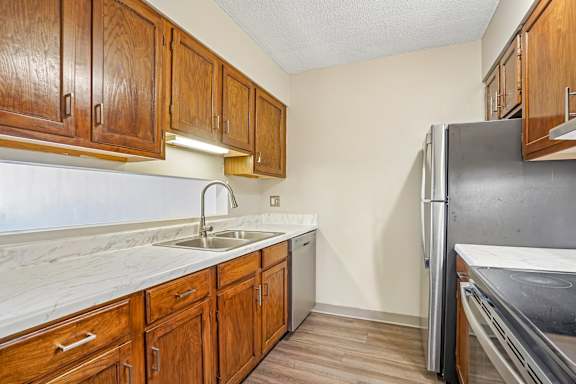 Irvine Park Towers kitchen with wood cabinetry, light countertops and open pass-through to the living room