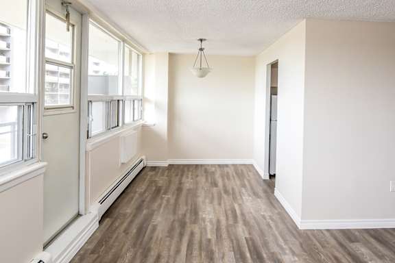 A room with wooden flooring and a window with blinds.