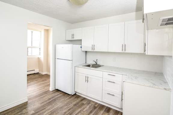 A kitchen with white cabinets and a white fridge.