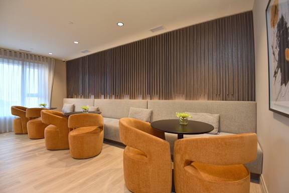A living room with orange chairs and a grey couch at Roxy Apartments, Hamilton, Ontario