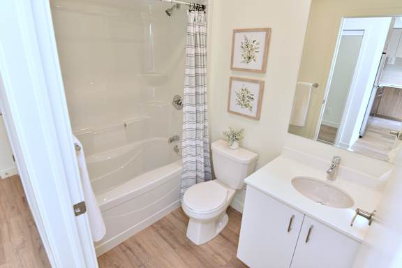 A white bathroom with a toilet, sink, and bathtub at Roxy Apartments, Hamilton, ON, L8H 0B7