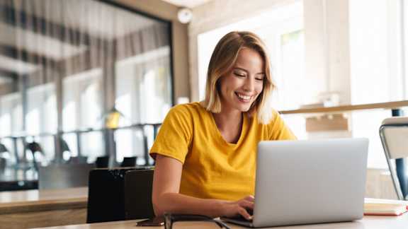 A woman in a yellow shirt is using a laptop at The Maverick Apartments, Kitchener, N2H 0E3
