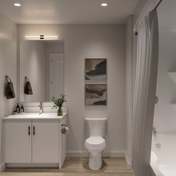 A white bathroom with a toilet, sink, and a painting on the wall at Roxy Apartments, Hamilton, ON