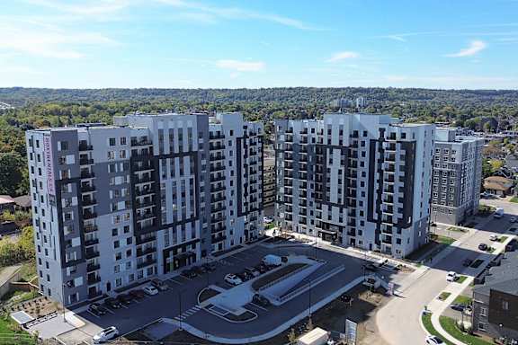 Two large buildings with a parking lot in between them at Roxy Apartments, Hamilton