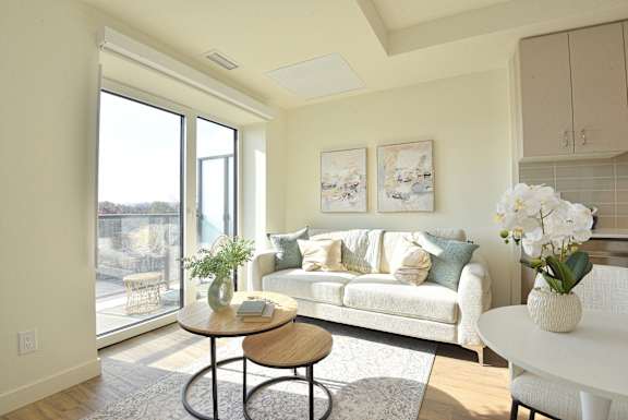 A living room with a white couch, a coffee table, and a large window at Roxy Apartments, Ontario, L8H 0B7