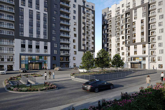 A car is driving down a street lined with modern apartment buildings.