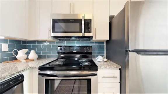 A kitchen with a black stove top oven and a refrigerator.at Cumberland Pointe, Smyrna, Georgia