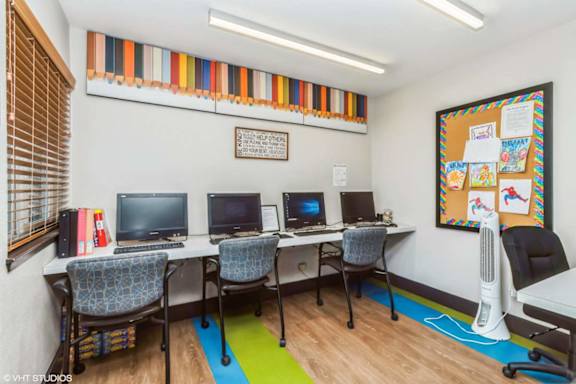 A room with a bulletin board and three computers.