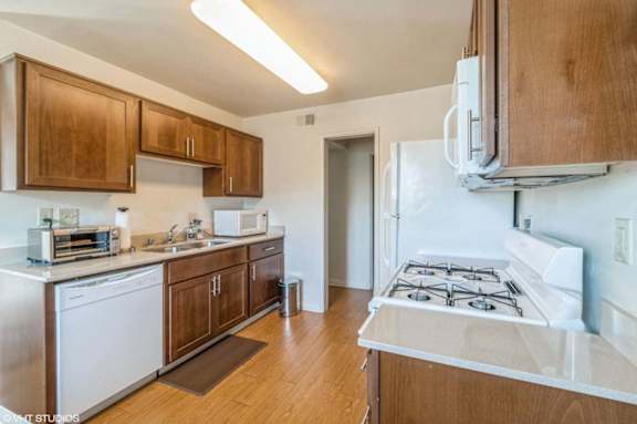A kitchen with wooden cabinets and a white stove top oven.