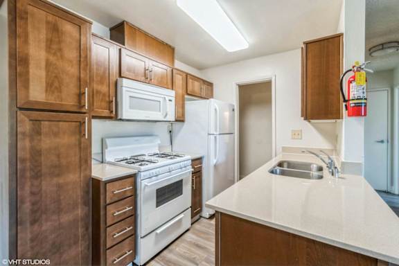 A kitchen with white appliances and wooden cabinets.
