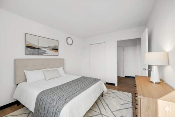 A bedroom with a large bed and a wooden nightstand.