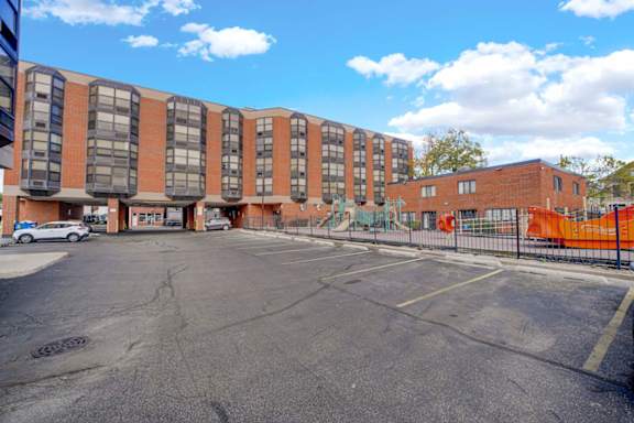 A parking lot in front of a multi-story brick building.