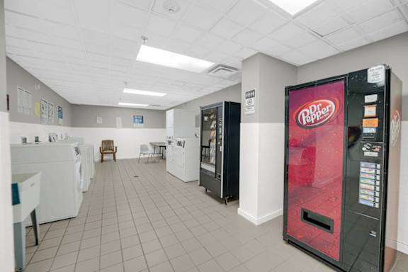 A Dr Pepper vending machine is in a room with washing machines.