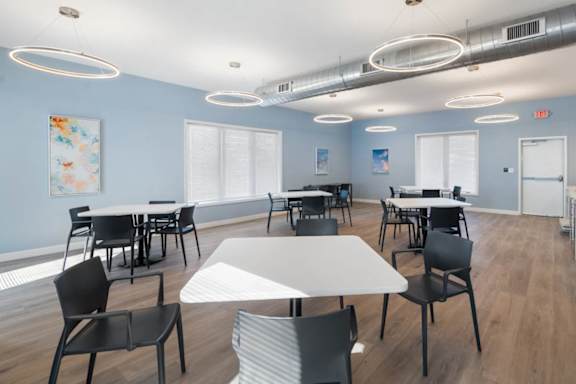 A room with tables and chairs and a painting on the wall.