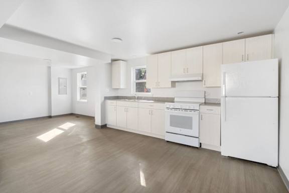A white kitchen with wood floors and white appliances.
