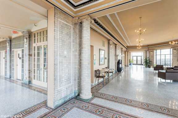 A spacious lobby with a marble floor and a chandelier hanging from the ceiling.