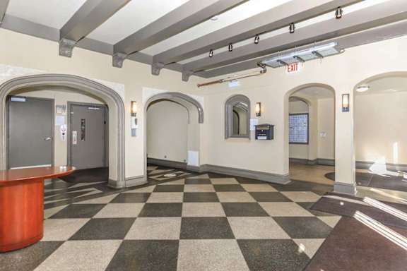 A hallway with a checkered floor and a red reception desk.