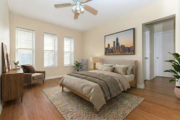 A bedroom with a bed, a couch, a painting, and a ceiling fan.