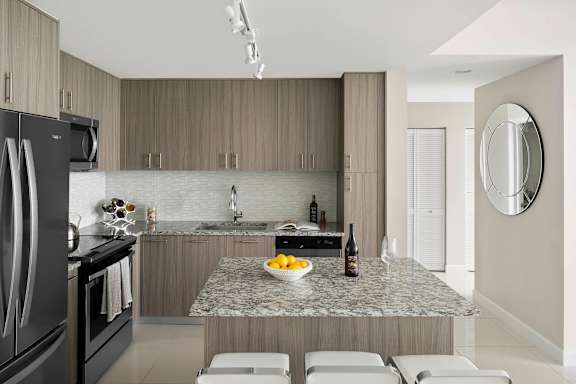 A modern kitchen with a granite countertop and stainless steel appliances. at Palma, Doral